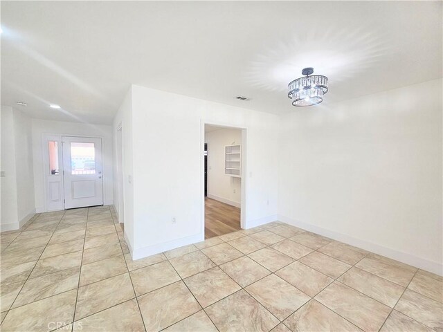 25687 Sandy Lodge Rd, Menifee, CA 92586 - unfurnished room featuring a chandelier, light tile patterned floors, and baseboards