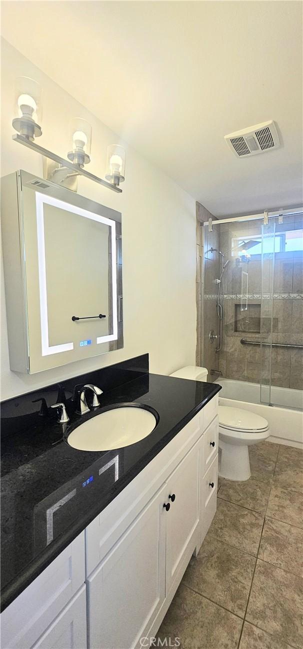 25687 Sandy Lodge Rd, Menifee, CA 92586 - full bathroom with vanity, toilet, tile patterned flooring, and combined bath / shower with glass door