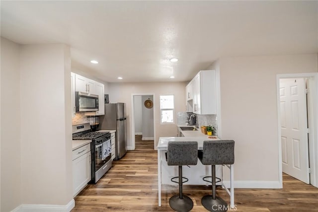 414 Iowa Ave, Riverside, CA 92507 - kitchen featuring appliances with stainless steel finishes, a breakfast bar area, wood finished floors, tasteful backsplash, and light countertops