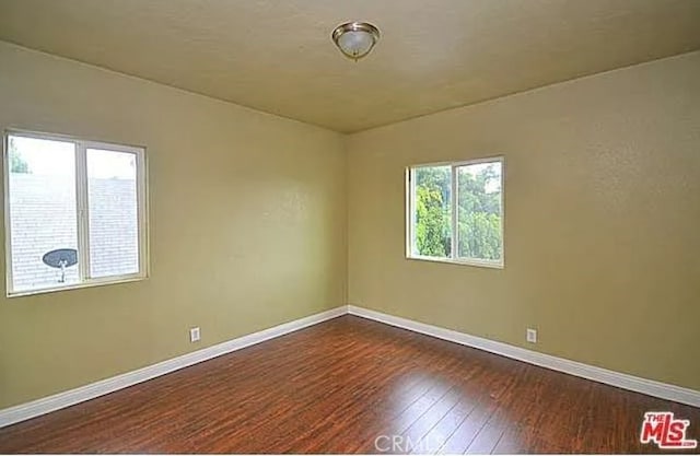 5102 Woodlawn Ave, Los Angeles, CA 90011 - spare room featuring dark wood-type flooring and baseboards