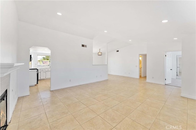 18346 Hackberry St, Hesperia, CA 92345 - unfurnished living room featuring light tile patterned floors, vaulted ceiling, arched walkways, recessed lighting, and a tiled fireplace
