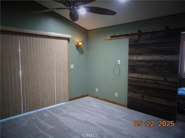 635 5th St, Willows, CA 95988 - unfurnished bedroom featuring carpet flooring, vaulted ceiling, a barn door, wooden walls, and a ceiling fan