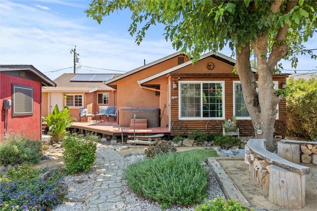 635 5th St, Willows, CA 95988 - back of house featuring a hot tub, a deck, roof mounted solar panels, and stucco siding