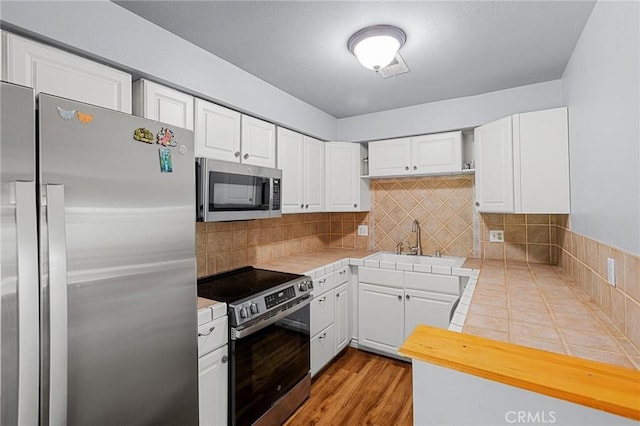 2061 Locust Ct, San Bernardino, CA 92404 - kitchen featuring appliances with stainless steel finishes, tile countertops, a sink, and white cabinetry
