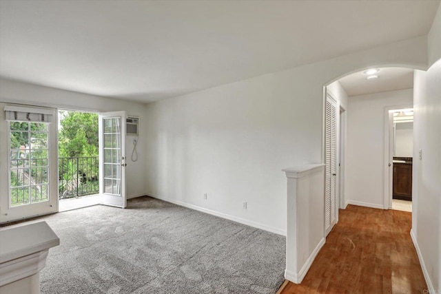 4570 54th St Unit 208, San Diego, CA 92115 - unfurnished room featuring arched walkways, baseboards, an AC wall unit, and wood finished floors