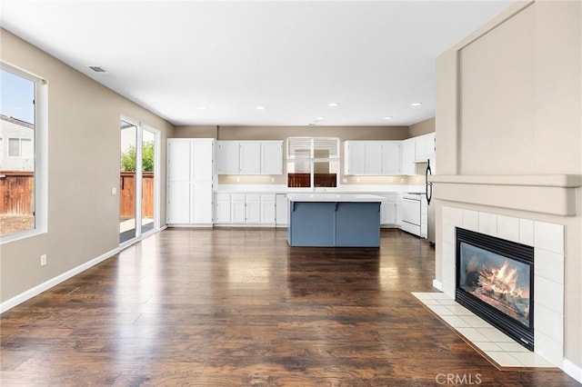 32702 Willowvail Cir, Temecula, CA 92592 - kitchen with a kitchen island, light countertops, dark wood-style flooring, a fireplace, and white cabinets