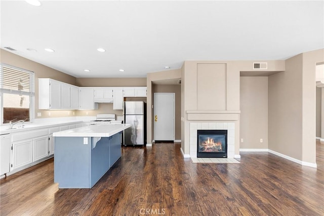 32702 Willowvail Cir, Temecula, CA 92592 - kitchen featuring freestanding refrigerator, a center island, light countertops, a fireplace, and white cabinets