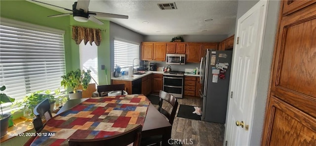 12609 Gentle Breeze Way, Victorville, CA 92392 - kitchen featuring appliances with stainless steel finishes, a ceiling fan, wood finished floors, brown cabinetry, and a sink