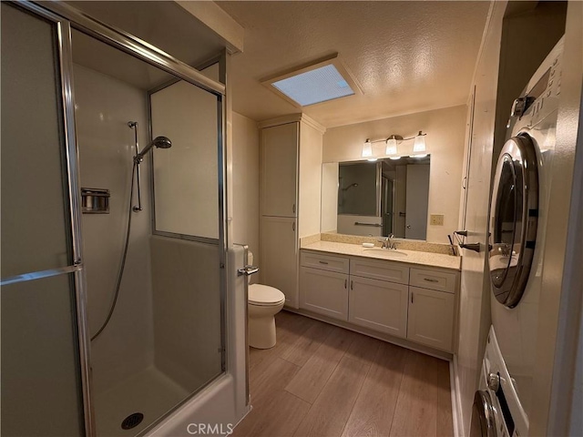 1533 Merion Way Unit 26K, Seal Beach, CA 90740 - bathroom featuring wood finished floors, a shower with shower door, vanity, washer / clothes dryer, and a textured ceiling