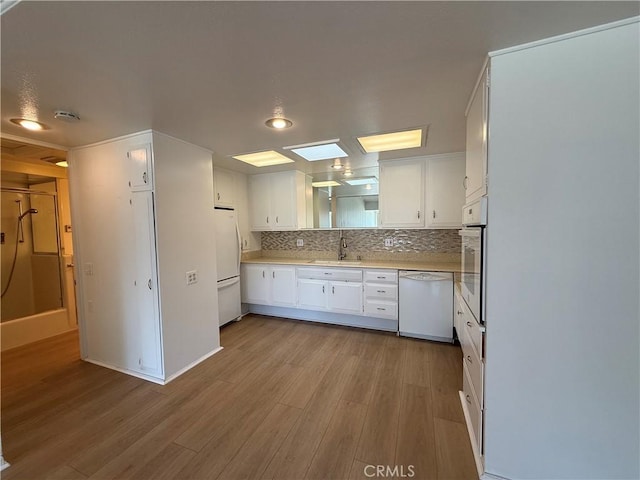 1533 Merion Way Unit 26K, Seal Beach, CA 90740 - kitchen with white appliances, light wood finished floors, white cabinetry, light countertops, and backsplash