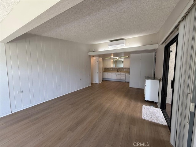 1533 Merion Way Unit 26K, Seal Beach, CA 90740 - unfurnished living room featuring an AC wall unit, dark wood-type flooring, and a textured ceiling