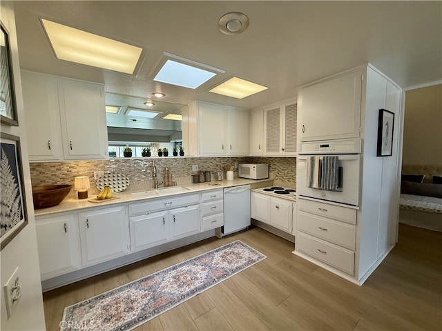 1533 Merion Way Unit 26K, Seal Beach, CA 90740 - kitchen featuring white appliances, wood finished floors, tasteful backsplash, white cabinetry, and light countertops