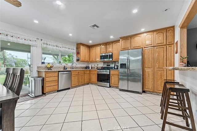 7669 Granby Ave, Rancho Cucamonga, CA 91730 - kitchen featuring stainless steel appliances, recessed lighting, brown cabinets, light stone countertops, and light tile patterned flooring