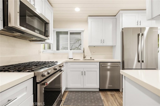 4735 Sunny Hills Rd, Oceanside, CA 92056 - kitchen with stainless steel appliances, a sink, wood finished floors, white cabinets, and light countertops