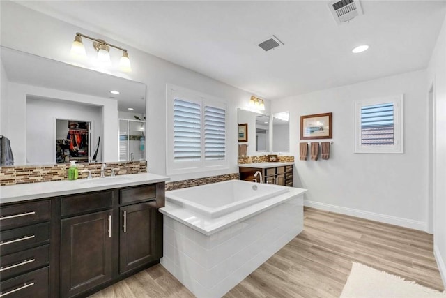 34253 Mazarine Dr, Temecula, CA 92592 - bathroom with a shower stall, two vanities, a bath, tasteful backsplash, and wood finished floors