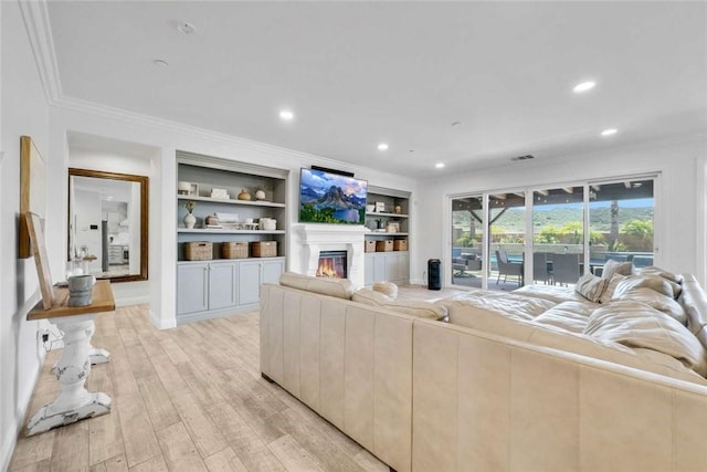 34253 Mazarine Dr, Temecula, CA 92592 - living room with crown molding, light wood-style floors, a glass covered fireplace, recessed lighting, and built in shelves