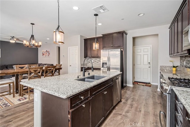 37436 Umbrella, Palmdale, CA 93551 - kitchen featuring a sink, appliances with stainless steel finishes, tasteful backsplash, dark brown cabinets, and light wood-style flooring