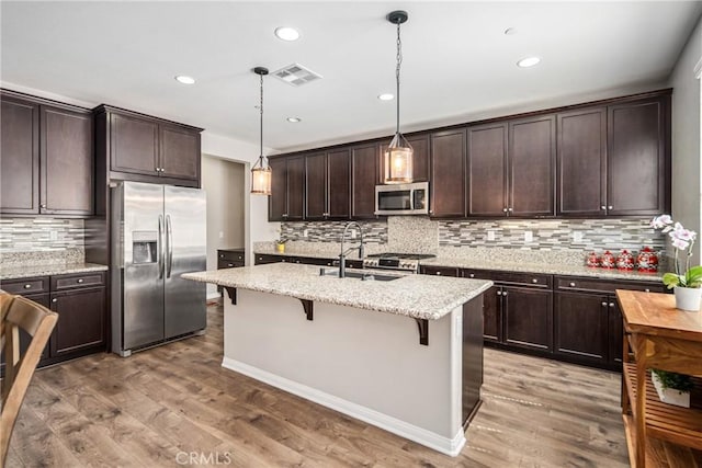 37436 Umbrella, Palmdale, CA 93551 - kitchen with stainless steel appliances, tasteful backsplash, a breakfast bar, dark brown cabinets, and light wood-style floors