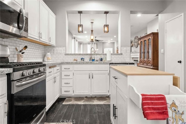 5191 Westerfield St, Jurupa Valley, CA 92509 - kitchen featuring appliances with stainless steel finishes, white cabinetry, dark wood-type flooring, tasteful backsplash, and a kitchen island