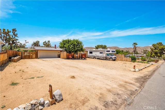 7608 Shawnee Trl, Yucca Valley, CA 92284 - view of front of home with driveway, a mountain view, and a garage