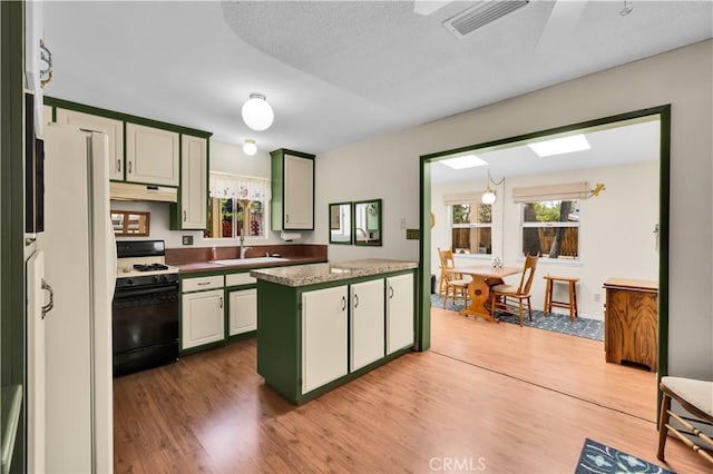 7608 Shawnee Trl, Yucca Valley, CA 92284 - kitchen with range with gas stovetop, under cabinet range hood, wood finished floors, and healthy amount of natural light