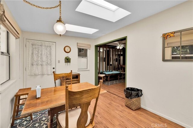 7608 Shawnee Trl, Yucca Valley, CA 92284 - dining space featuring a skylight, light wood-style flooring, and baseboards