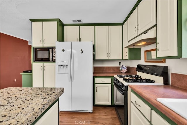 7608 Shawnee Trl, Yucca Valley, CA 92284 - kitchen with black appliances, under cabinet range hood, wood finished floors, a sink, and light countertops