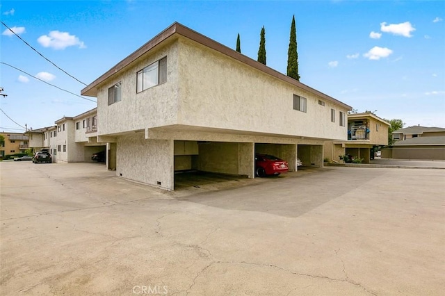 121 E Live Oak St, San Gabriel, CA 91776 - view of side of home featuring stucco siding, covered parking, and a residential view