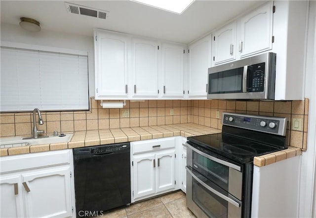 5030 Cardiff Ln, Atwater, CA 95301 - kitchen featuring appliances with stainless steel finishes, white cabinetry, backsplash, and light tile patterned flooring