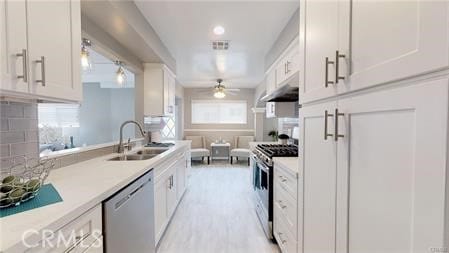 6008 Amos Ave, Lakewood, CA 90712 - kitchen with stainless steel appliances, ceiling fan, under cabinet range hood, light countertops, and white cabinetry