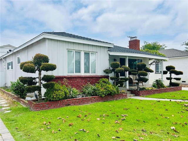 6008 Amos Ave, Lakewood, CA 90712 - view of home's exterior with board and batten siding, a lawn, a chimney, and brick siding