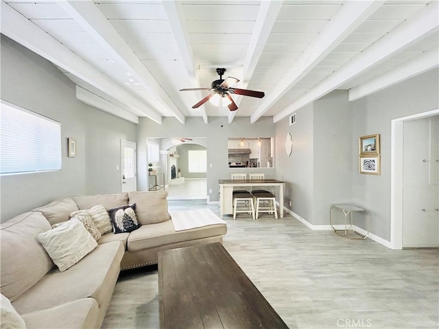 6008 Amos Ave, Lakewood, CA 90712 - living area with ceiling fan, arched walkways, light wood-style floors, beamed ceiling, and plenty of natural light