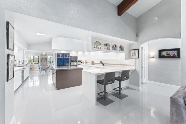 19 Gateview Dr, Fallbrook, CA 92028 - kitchen featuring white cabinetry, glass insert cabinets, a kitchen breakfast bar, light tile patterned flooring, and a towering ceiling