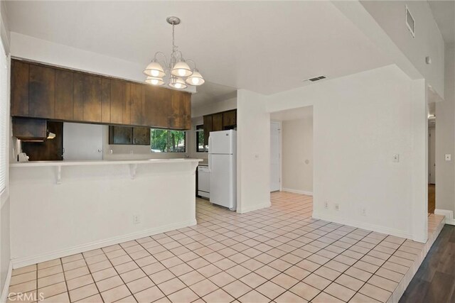1018 Greenwich Dr, Chico, CA 95926 - kitchen with white appliances, light countertops, a peninsula, a breakfast bar, and a chandelier