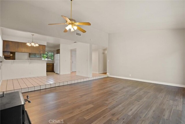 1018 Greenwich Dr, Chico, CA 95926 - unfurnished living room featuring a ceiling fan, a chandelier, light wood-style floors, baseboards, and lofted ceiling