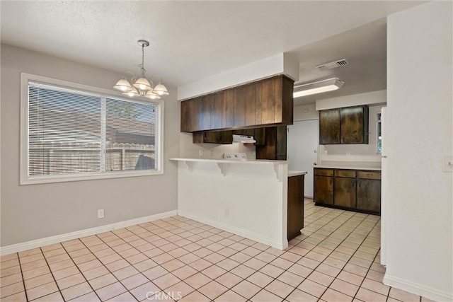 1018 Greenwich Dr, Chico, CA 95926 - kitchen featuring a chandelier, light countertops, a peninsula, a kitchen bar, and light tile patterned floors