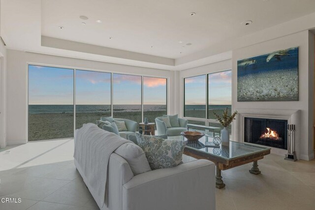 1135 Capri Way, Oxnard, CA 93035 - living area featuring a lit fireplace, light tile patterned floors, a water view, and a raised ceiling