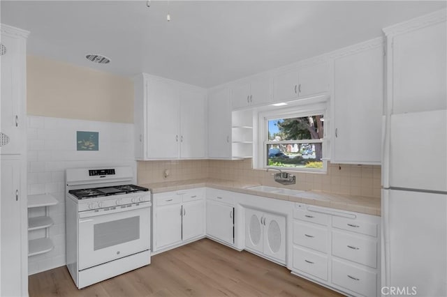 11046 Howard St, Whittier, CA 90606 - kitchen featuring white appliances, tile countertops, white cabinetry, light wood-style floors, and tasteful backsplash