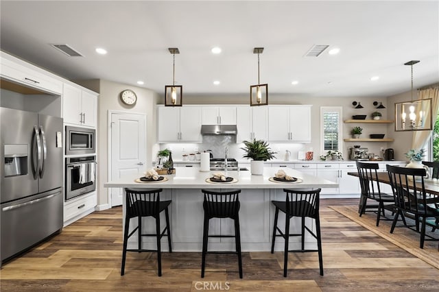 24 Granja Ct, Rancho Mission Viejo, CA 92694 - kitchen with appliances with stainless steel finishes, light countertops, a kitchen island with sink, white cabinets, and a kitchen bar