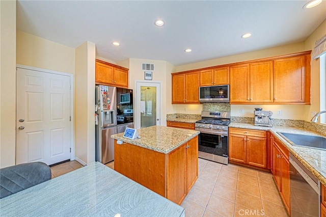 25238 Gloriso Ln, Stevenson Ranch, CA 91381 - kitchen featuring stainless steel appliances, a sink, light tile patterned flooring, a kitchen island, and brown cabinets