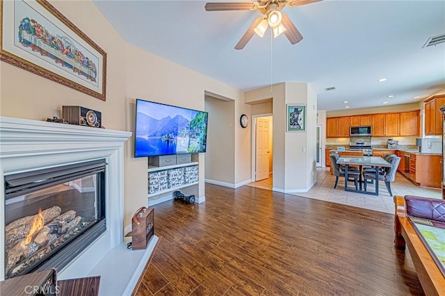 25238 Gloriso Ln, Stevenson Ranch, CA 91381 - living room featuring light wood-style floors, a glass covered fireplace, baseboards, a ceiling fan, and recessed lighting