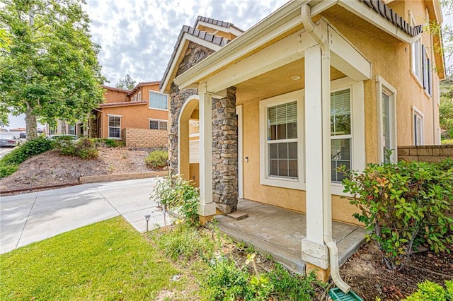 25238 Gloriso Ln, Stevenson Ranch, CA 91381 - view of side of property featuring stone siding, covered porch, and stucco siding