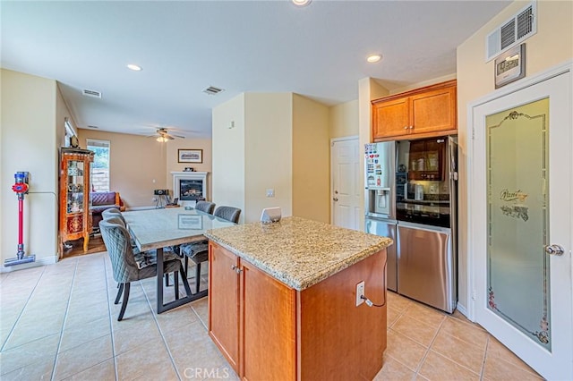 25238 Gloriso Ln, Stevenson Ranch, CA 91381 - kitchen featuring stainless steel refrigerator with ice dispenser, a kitchen island, light tile patterned flooring, a glass covered fireplace, and open floor plan