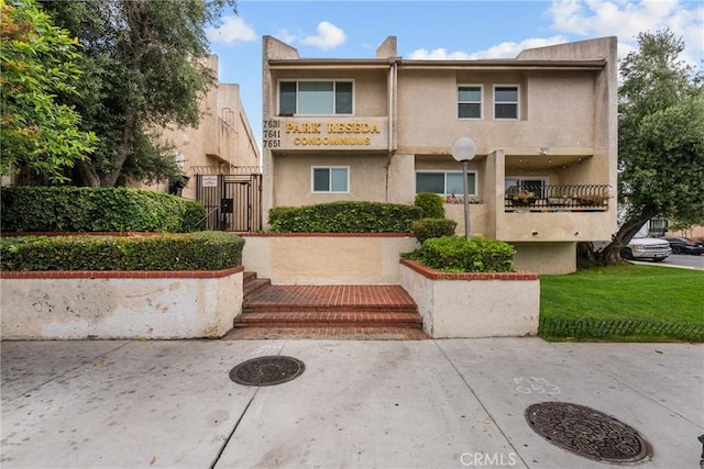 7641 Reseda Blvd Unit 108Z, Reseda, CA 91335 - view of property featuring stucco siding, a gate, and a front lawn