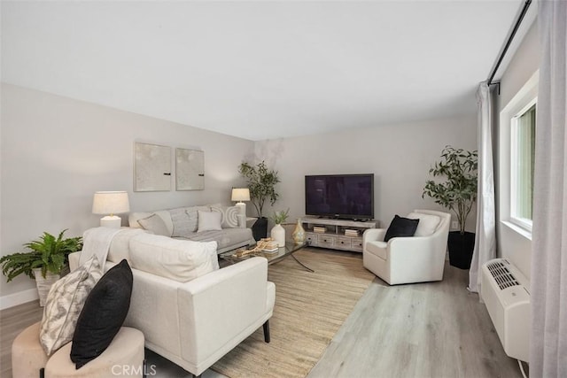 3241 San Amadeo Unit 1G, Laguna Woods, CA 92637 - living room with wood finished floors, a wall mounted AC, and baseboards