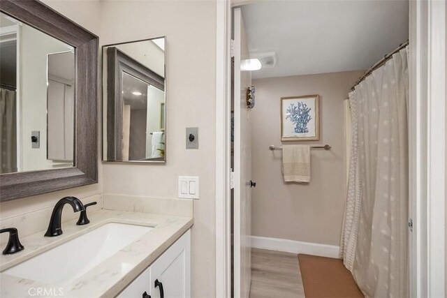 3241 San Amadeo Unit 1G, Laguna Woods, CA 92637 - full bath with vanity, baseboards, and wood finished floors
