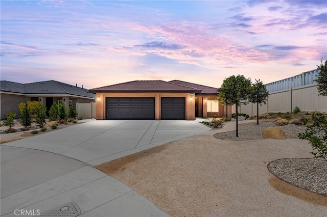 1243 Ansley Ln, Mentone, CA 92359 - view of front of house featuring an attached garage, driveway, a tiled roof, and stucco siding
