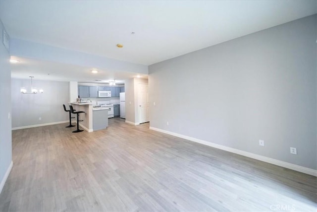 31241 Taylor Ln, Temecula, CA 92592 - unfurnished living room with a chandelier, baseboards, and light wood-type flooring