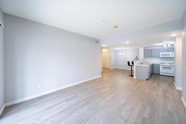 31241 Taylor Ln, Temecula, CA 92592 - unfurnished living room with baseboards, light wood-style flooring, a sink, and a chandelier