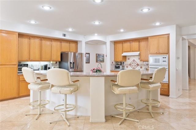 12830 Wildflower Ln, Riverside, CA 92503 - kitchen with white microwave, oven, stainless steel fridge, tasteful backsplash, and recessed lighting
